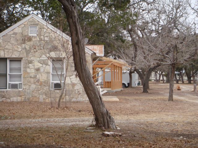 A tree in front of a house with a building behind it.