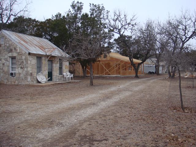 A dirt road with two houses and trees