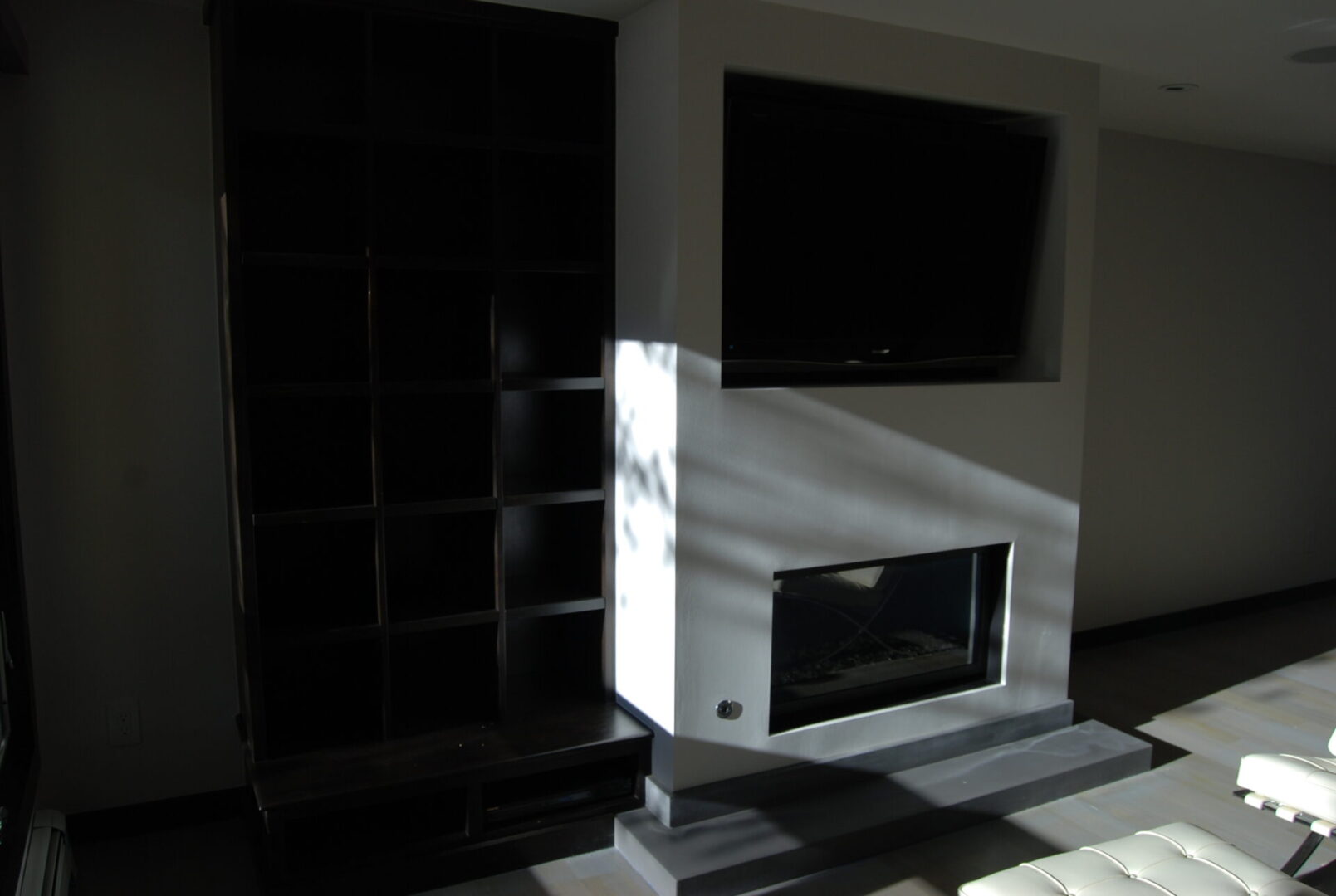 A fireplace in the corner of a room with shelves.