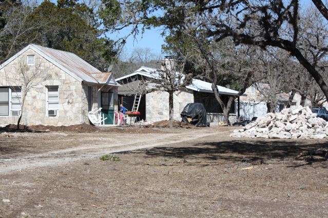 A dirt road with some houses and trees