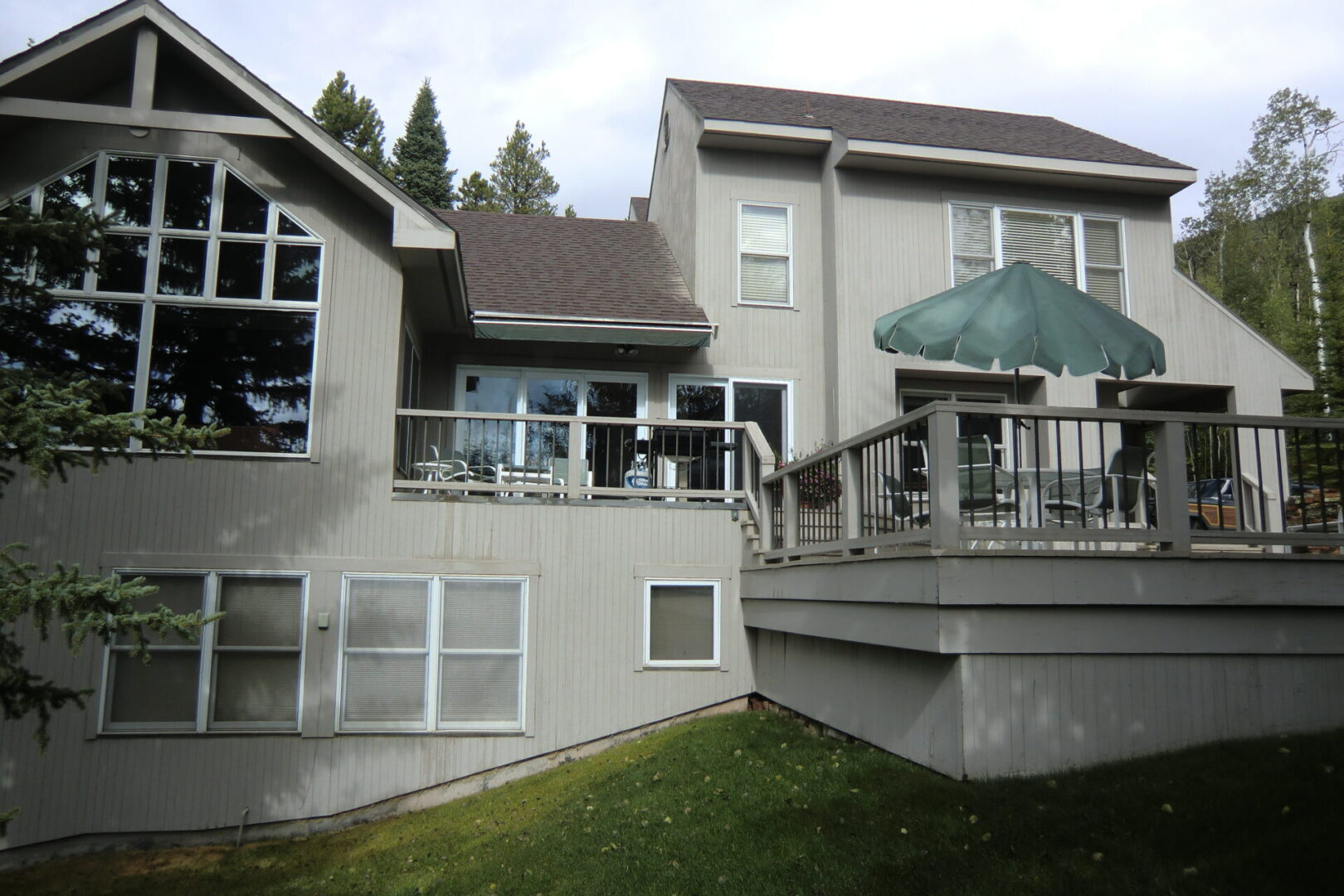 A large house with a patio umbrella on the back deck.