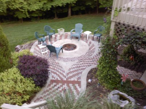 A patio with chairs and fire pit in the middle of it.