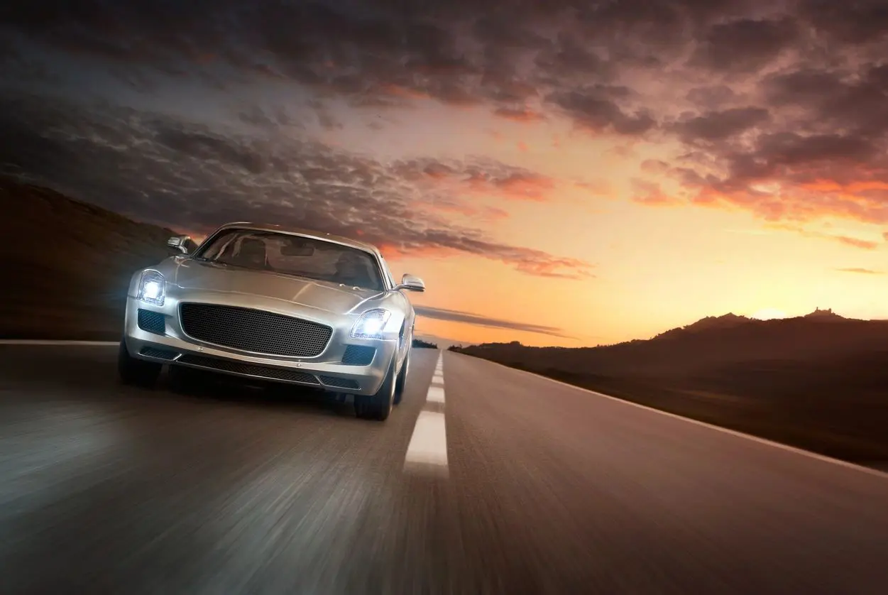 A car driving down the road at sunset.