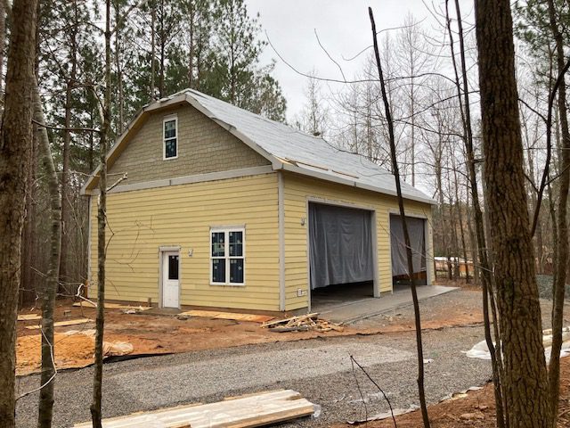 A yellow barn with a metal roof and a door.